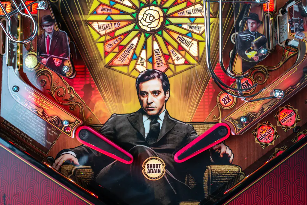 Le centre du plateau du flipper The Godfather : un portrait d’homme en costume sombre, assis, sous une rosace de vitrail éclairée.