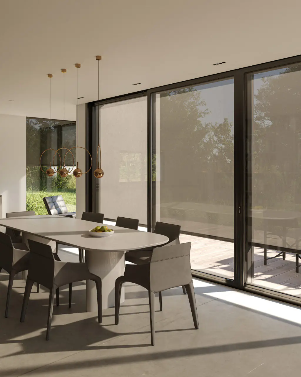 Salle à manger contemporaine vue de l’intérieur : stores screen extérieurs descendus devant de grandes baies à cadre noir, la toile laisse deviner les arbres et la terrasse ; table ovale, chaises taupe, suspensions cuivrées. Format portrait.