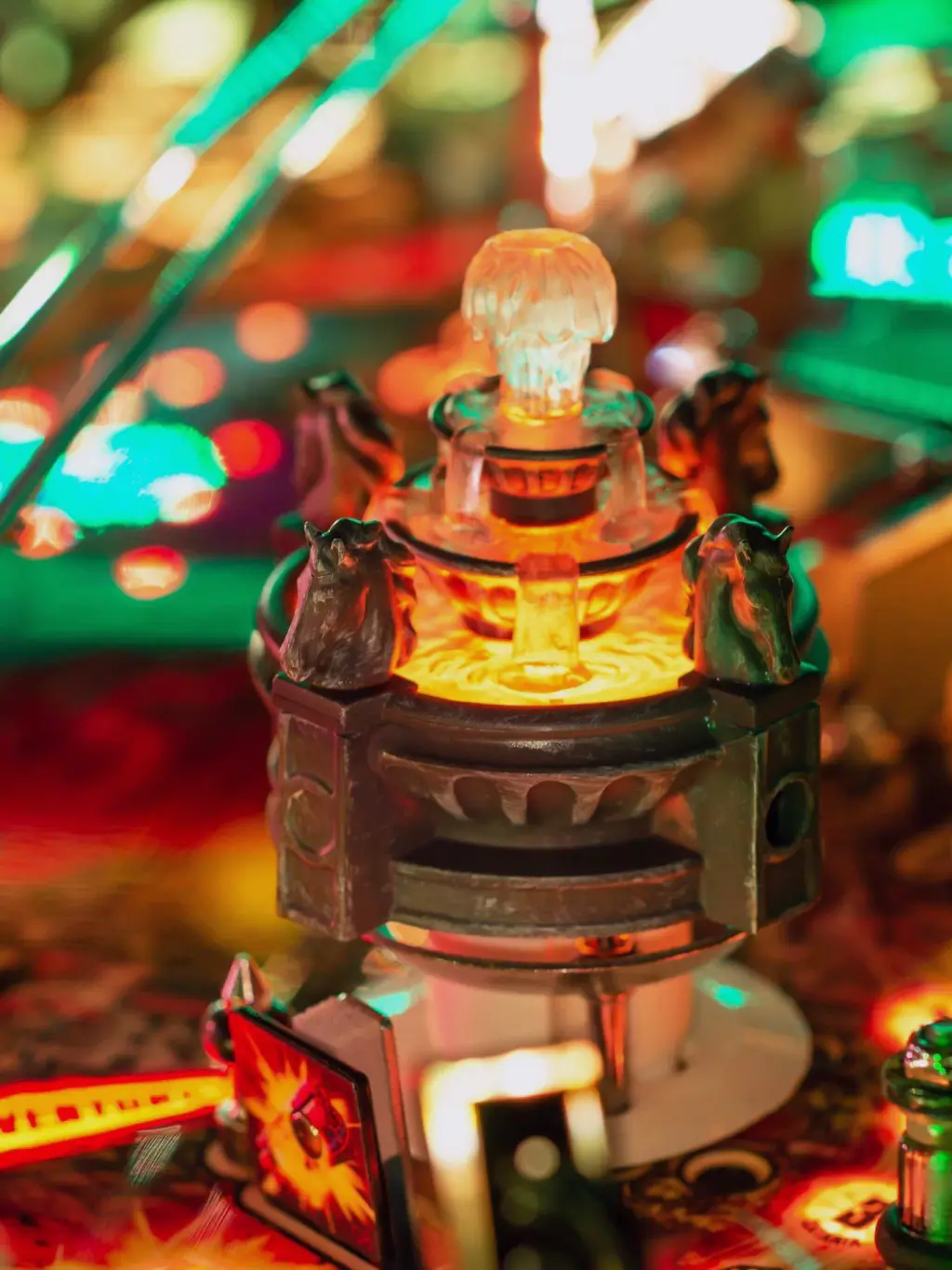 Gros plan sur le plateau allumé d’un flipper Jersey Jack Pinball The Godfather : une petite tour sculptée éclairée de l’intérieur, des lumières ambrées et rouges floues autour.