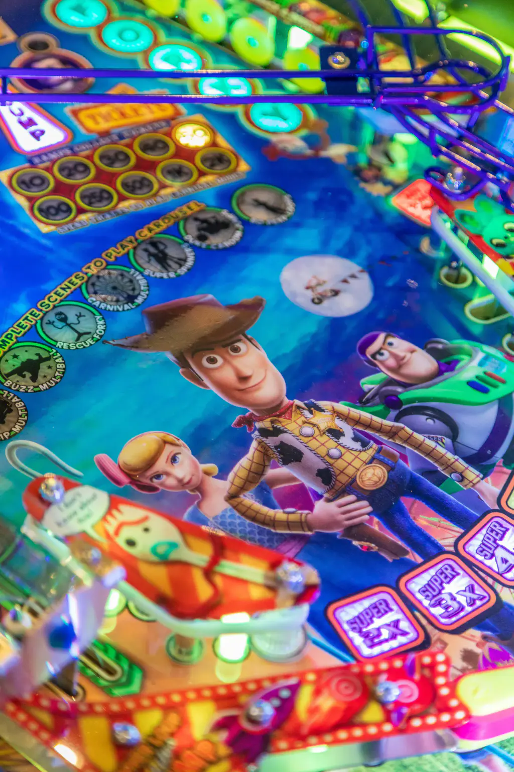 Le plateau vu au ras de la vitre : les personnages du film peints sur fond bleu, des inserts ronds en arc, une grille de tickets et une rampe en fil violet au fond.