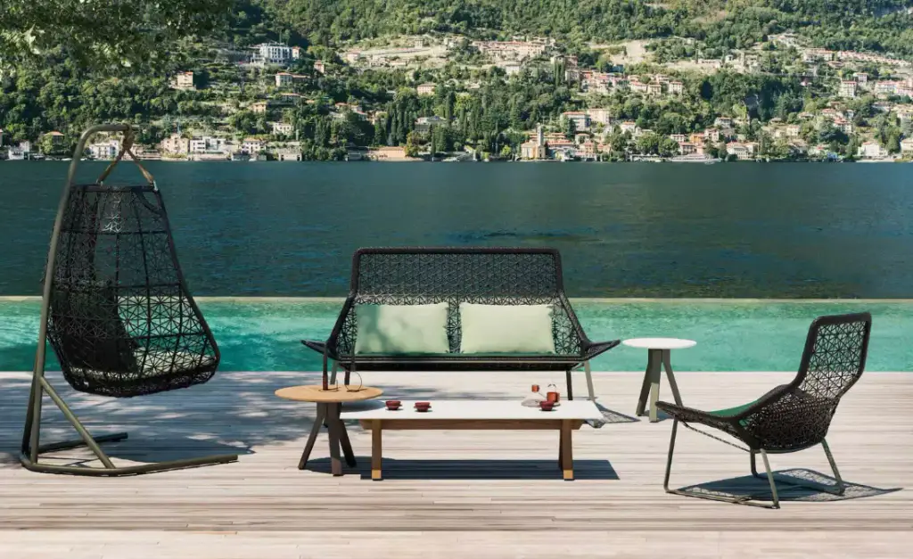 Visuel de fournisseur : fauteuil suspendu tressé, banquette et table basse sur un ponton, au bord d’un lac.