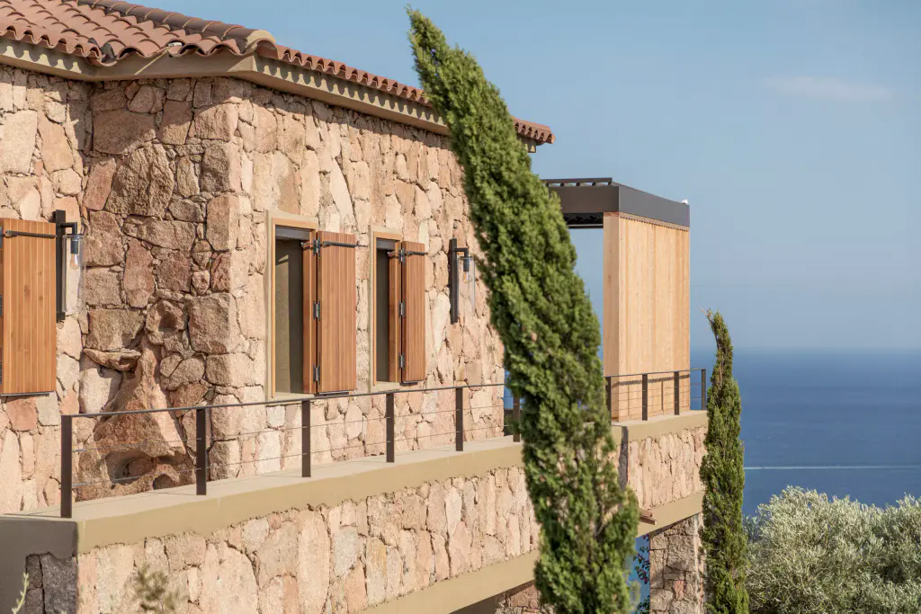 Stone house, cypresses, shutters and wooden privacy screen, blue sea.