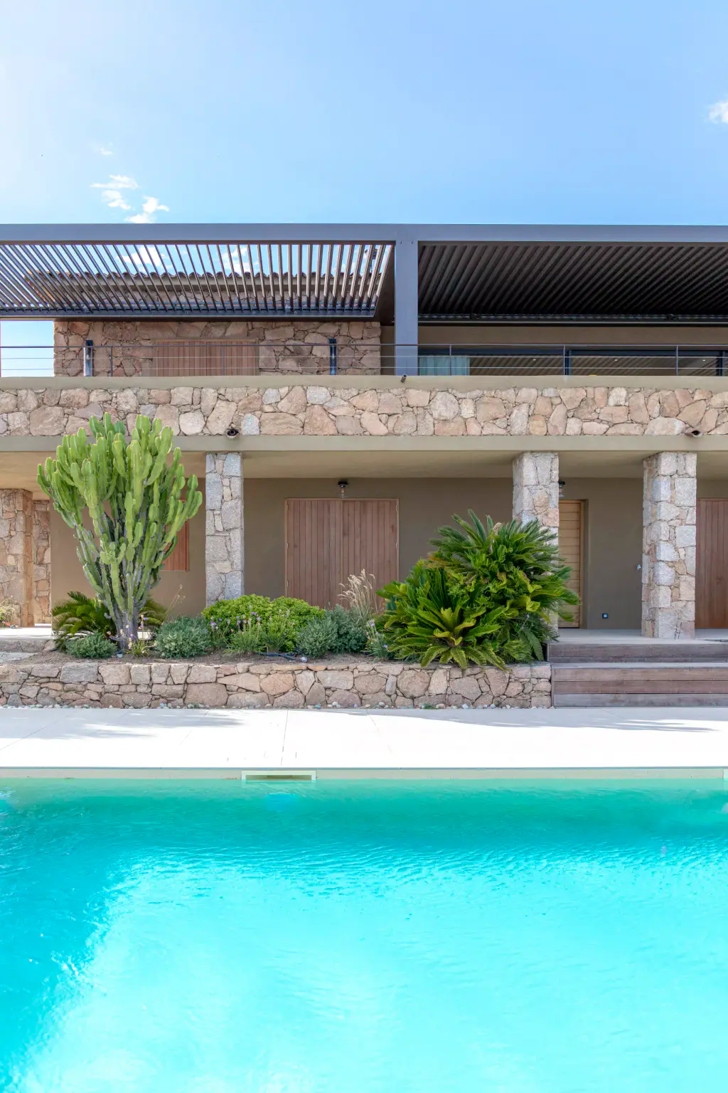 Turquoise pool in the lower half, a two-storey stone villa topped by the anthracite pergola.