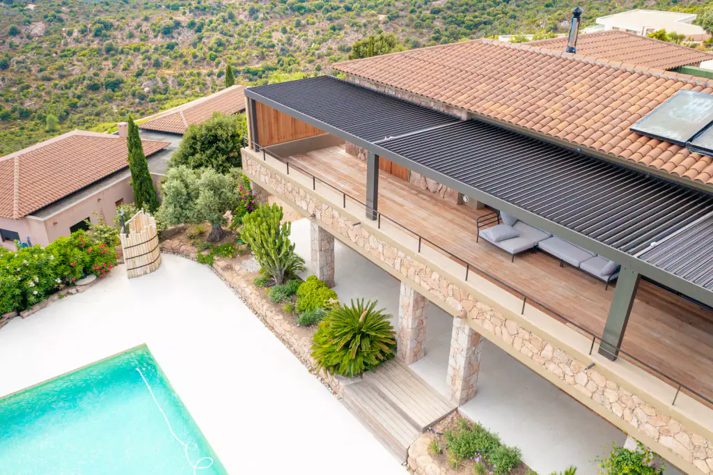 Drone view: anthracite pergola on the upper-floor terrace, tiled roof, pool below.