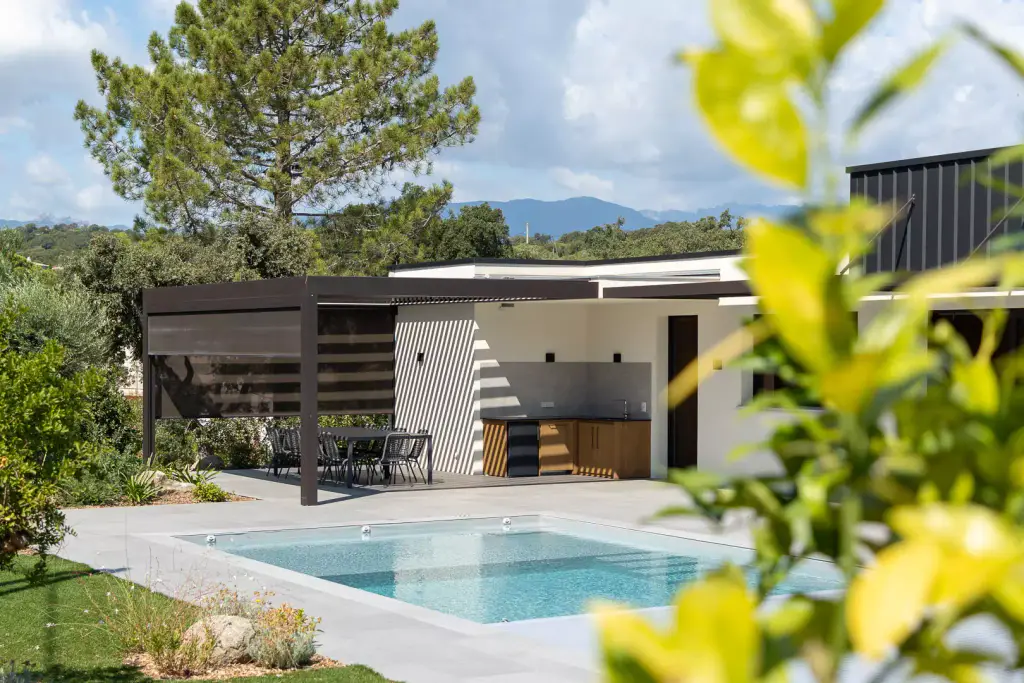 Anthracite pergola over the summer kitchen and small pool, blurred yellow foliage in the foreground, mountains.