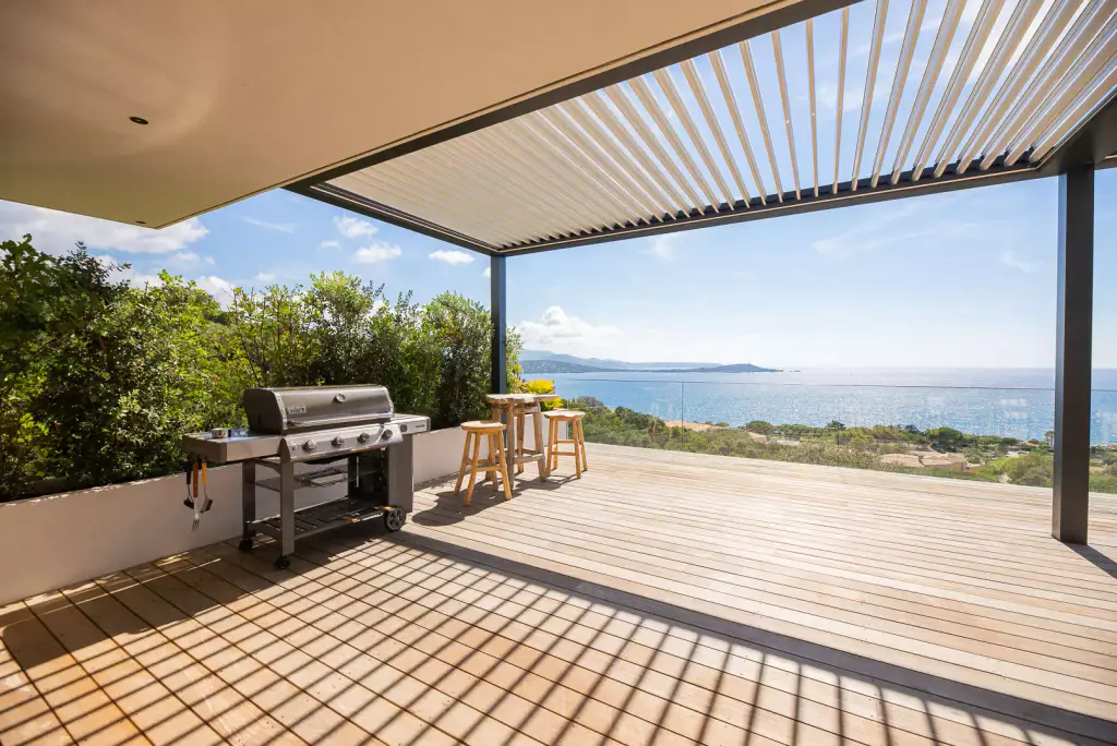 Louvres fanned open, stainless steel barbecue, high table, deck and sea.