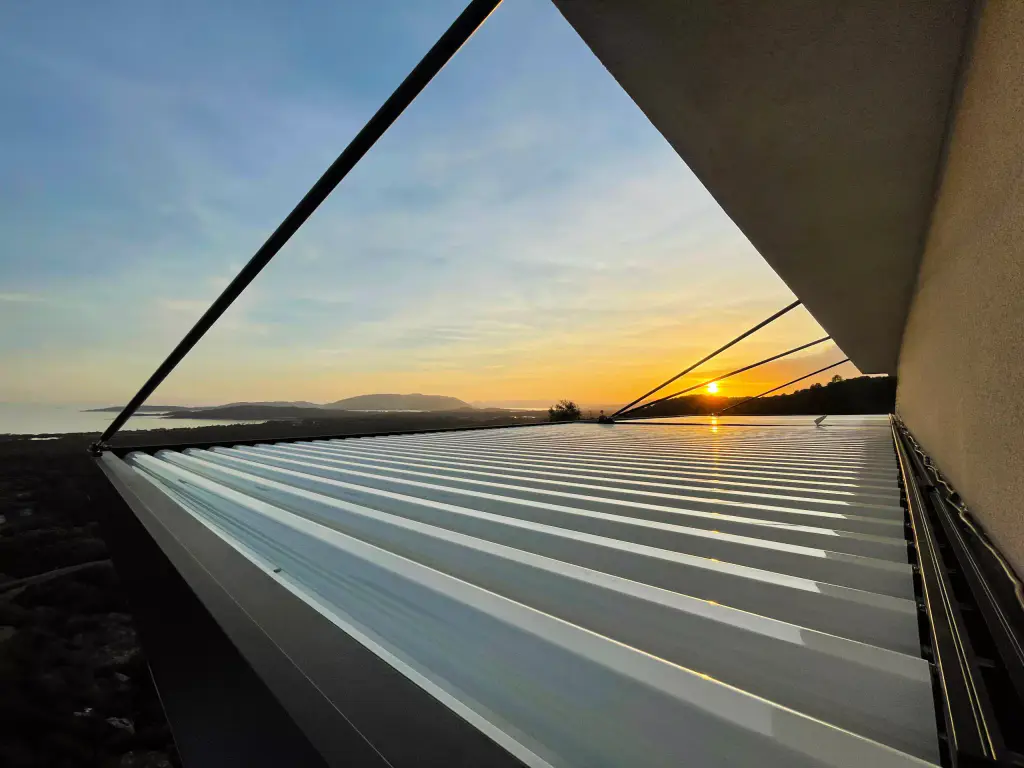 Top of the pergola (light louvres) at sunset, triangular structure in silhouette, gulf.