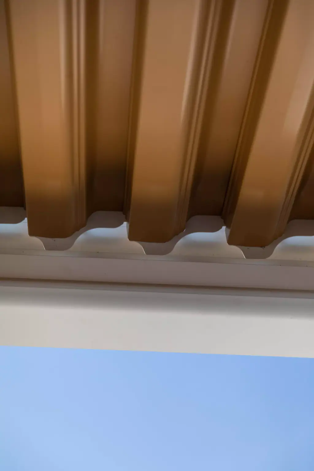 Détail du profil des lames en bout et du cadre blanc, ciel bleu.