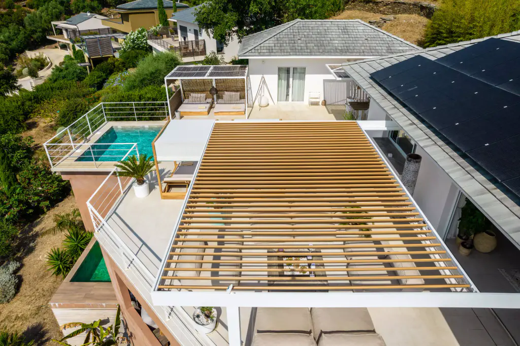 Vue drone plongeante : pergola, piscine, lit à baldaquin, maquis.