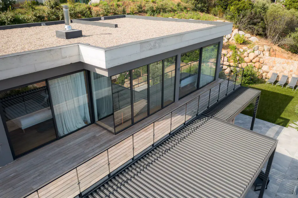Drone view: gravel roof of the villa at the top, pergola below, lawn.