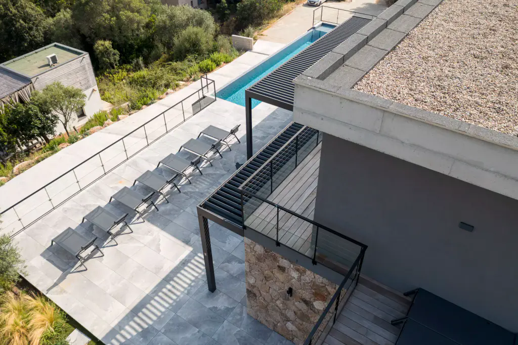 Downward drone view: row of loungers, swimming lane, corner of the pergola.