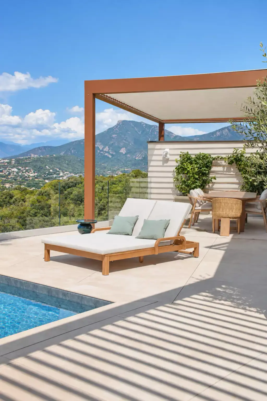 Pergola bioclimatique brun cuivré adossée à la maison, face à la montagne ; dessous, un bain de soleil double en teck, et au sol l’ombre rayée d’une seconde pergola.