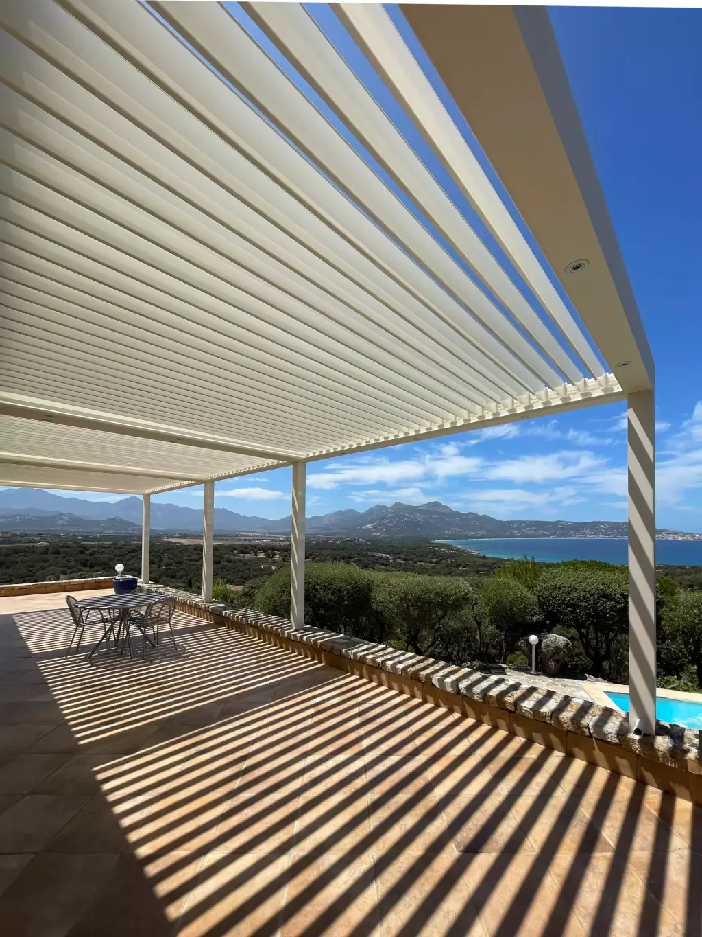 Under the white pergola, portrait format: half-open louvres, striped shadows, gulf.