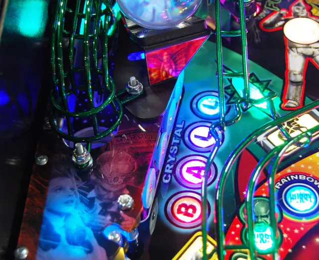 Gros plan du plateau du flipper Wizard of Oz : une boule de cristal éclairée, des inserts bleus et une rampe verte.