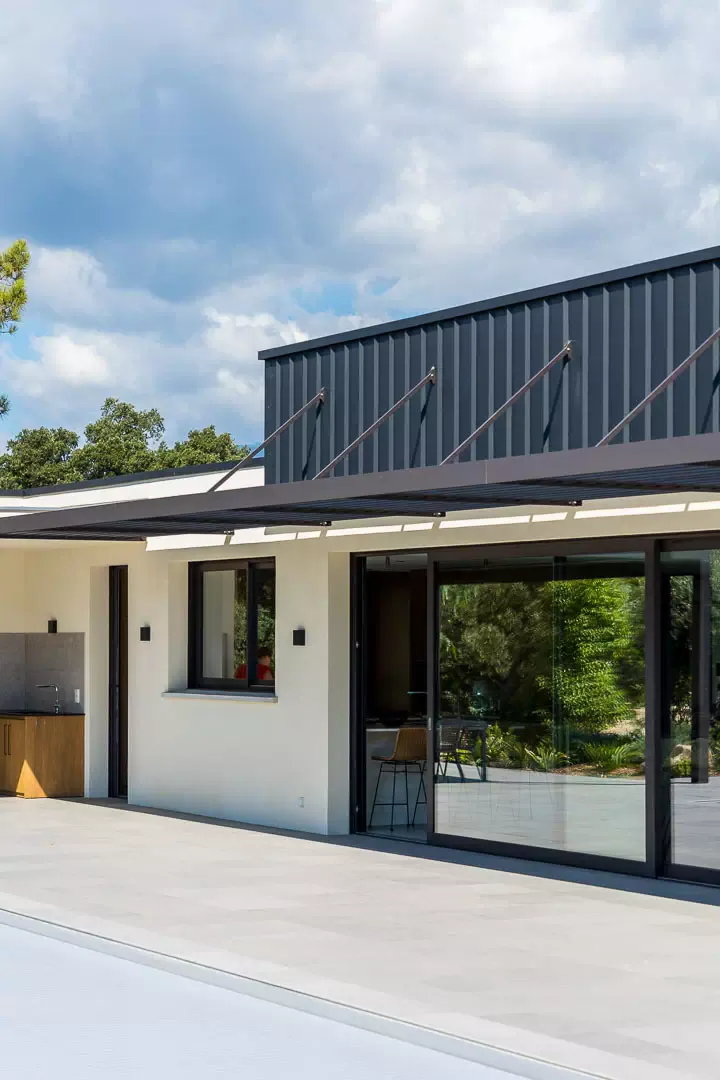 Façade with a cable-stayed brise-soleil canopy, glazed opening, zinc cladding.